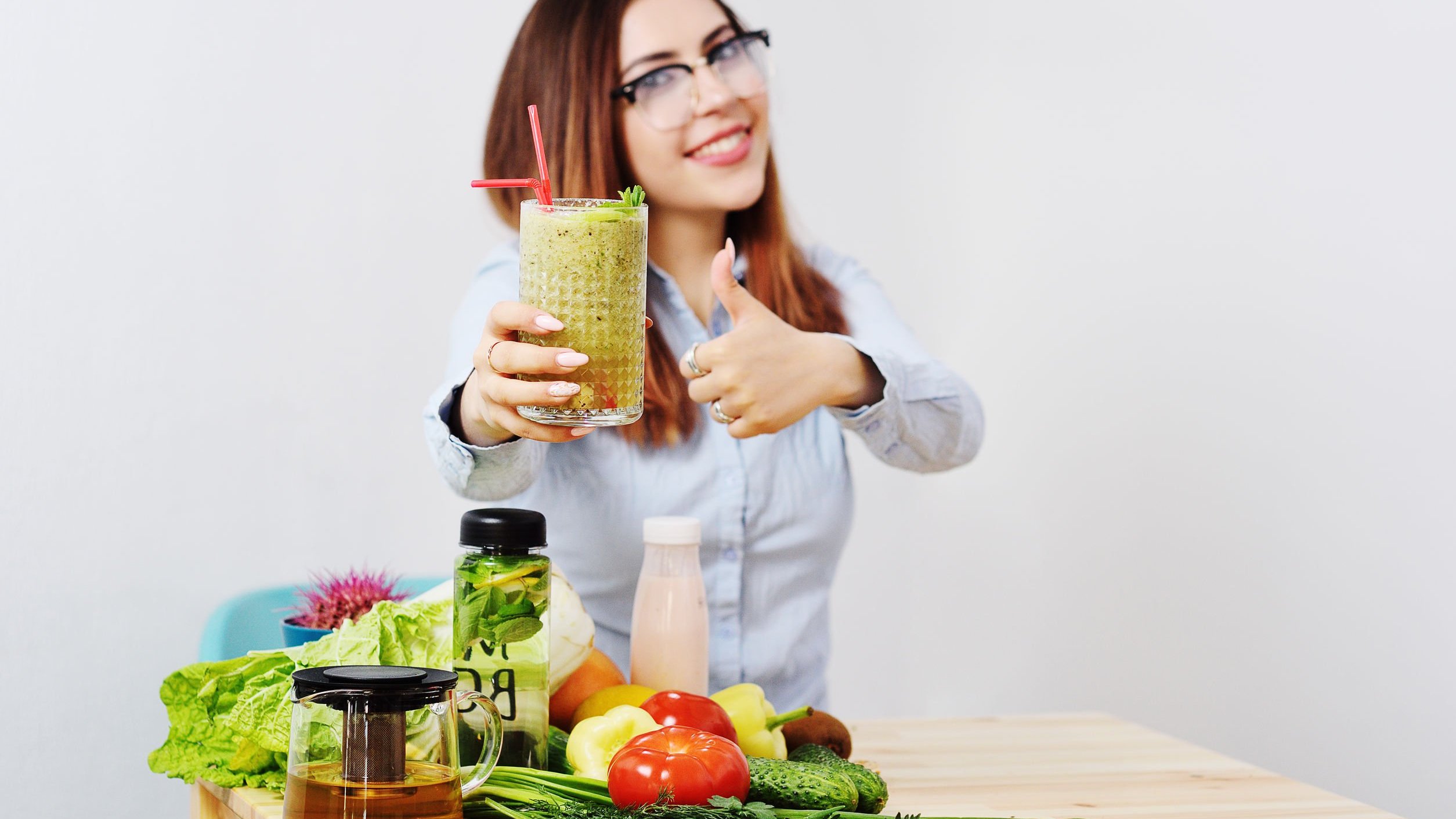 Mulher de óculos, sorrindo segurando copo de suco verde