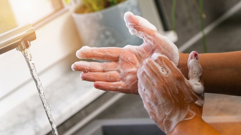 Pessoa lavando as mãos com sabão na pia