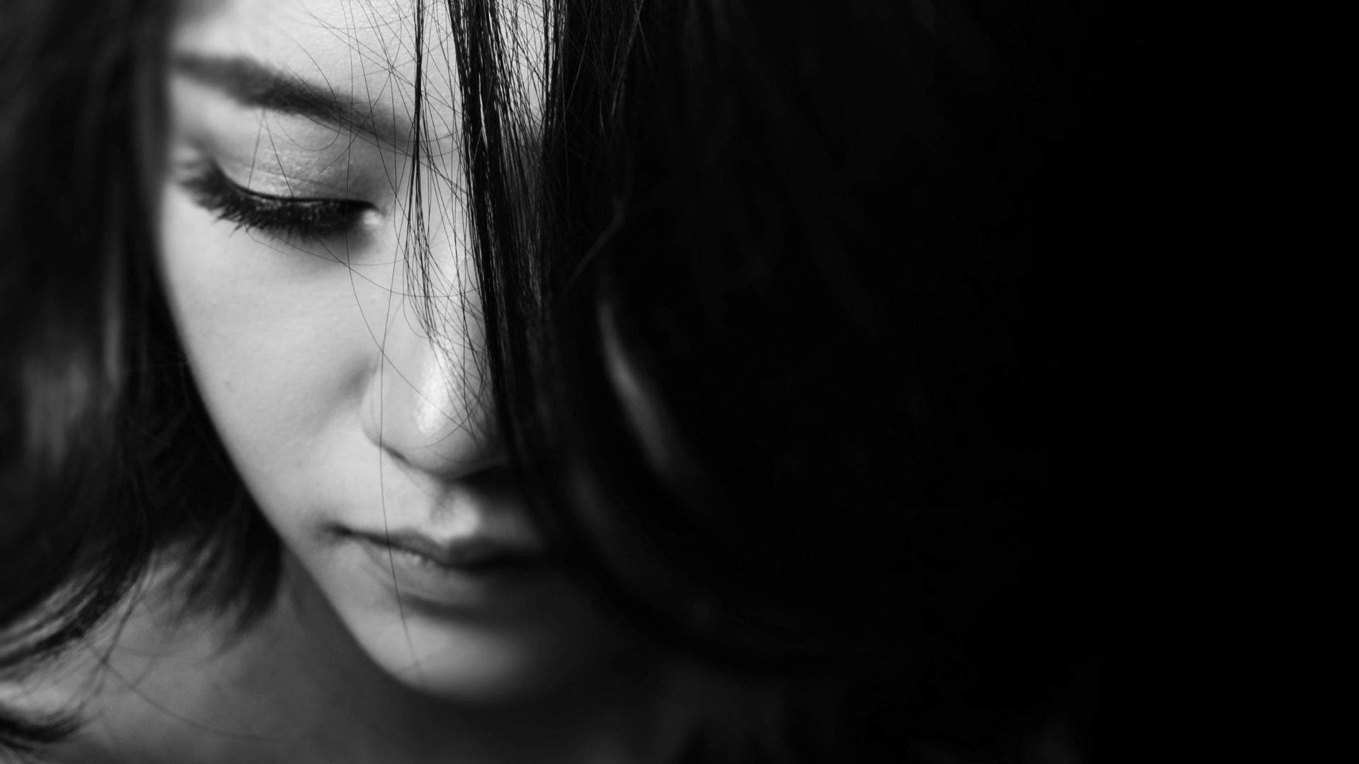 Imagem em preto e branco de uma mulher de cabeça baixa e triste