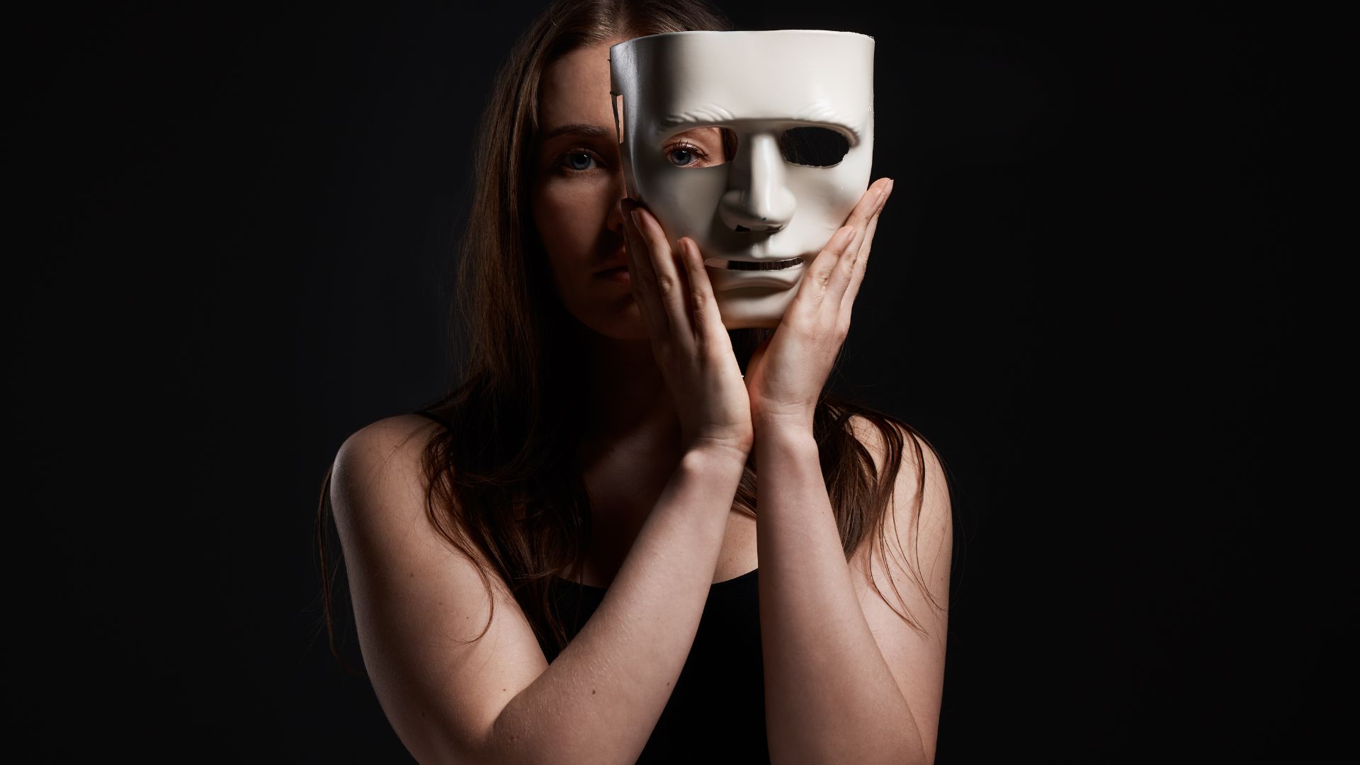 Imagem de uma mulher tirando uma máscara do rosto em um fundo preto