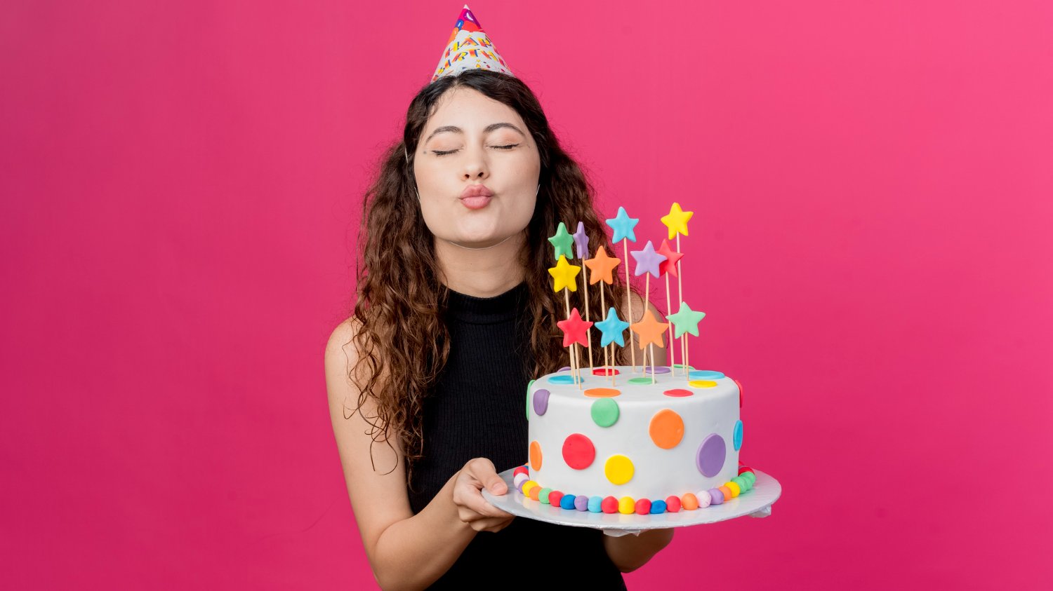 stockking / Freepik Menina branca de cabelos cacheados e castanhos segurando um bolo decorado