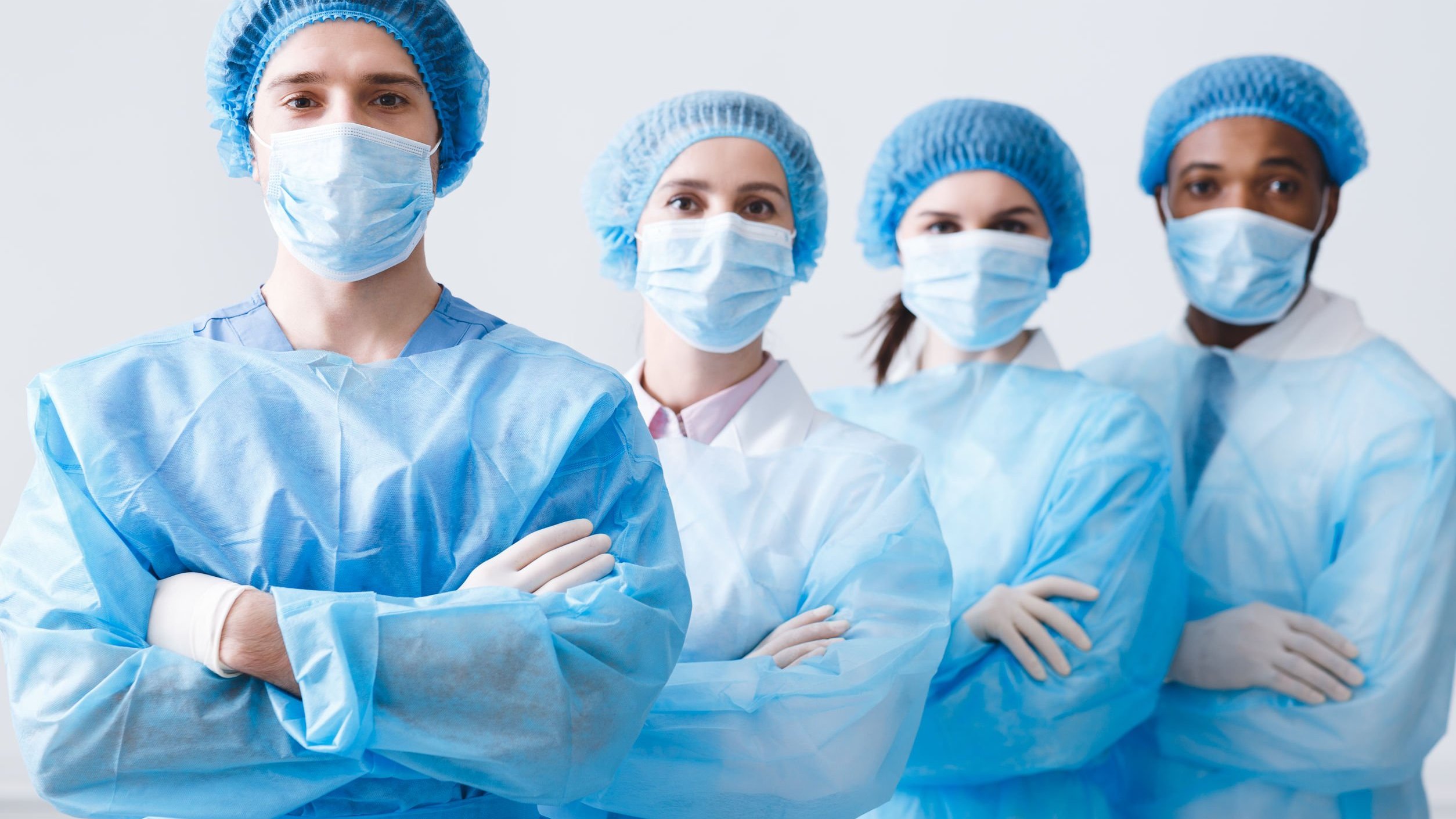 Quatro médicos usando roupas e acessórios cirúrgicos.
