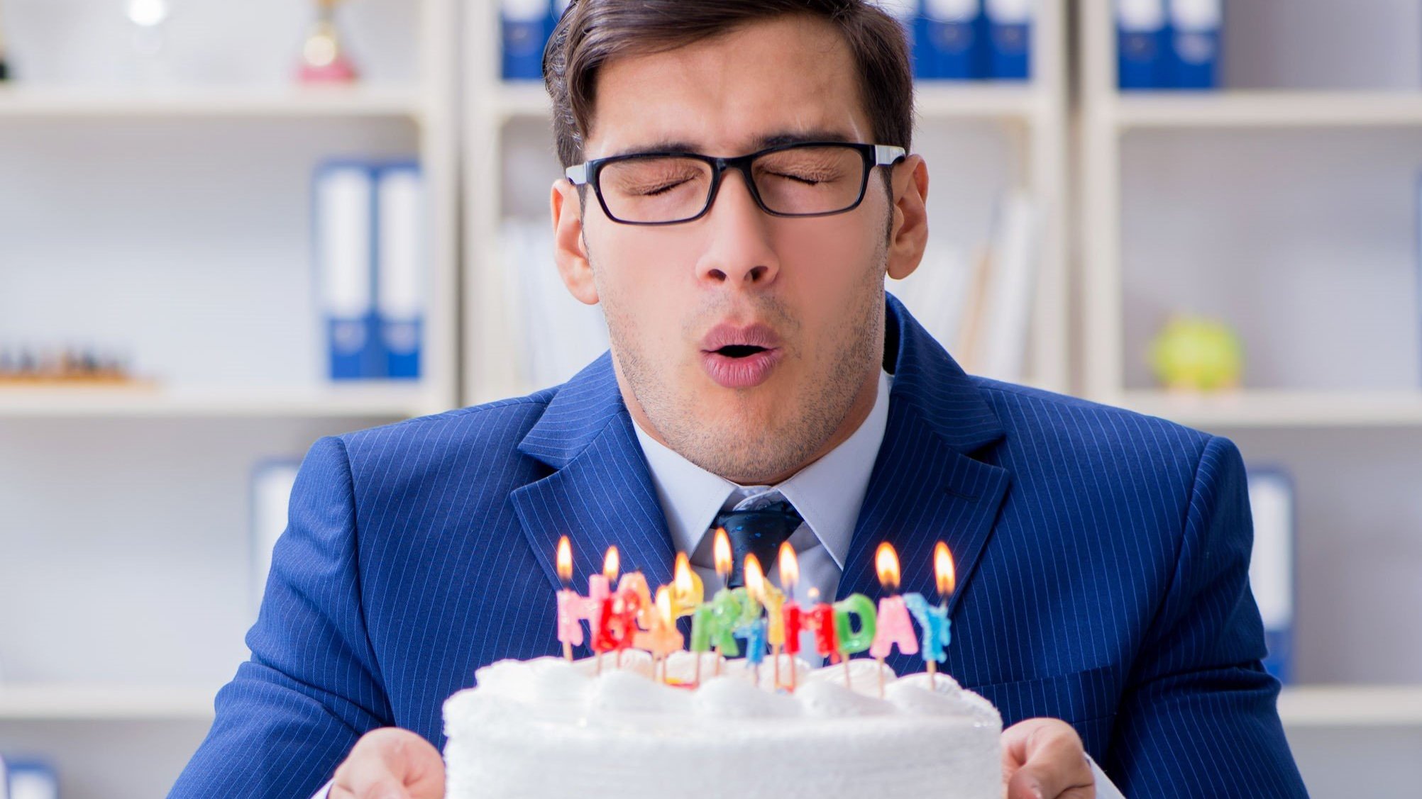 Homem assoprando velas do bolo.