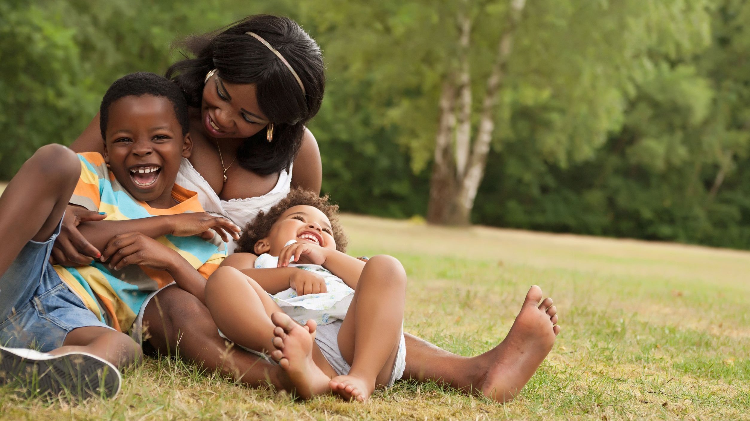 Mãe sentada no gramado com seus filhos