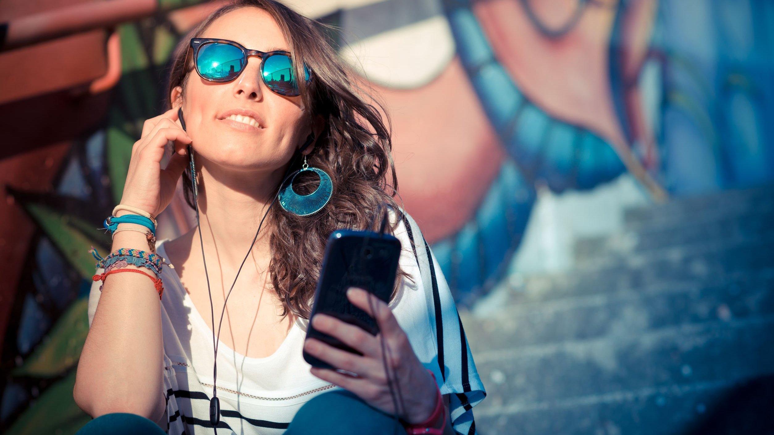 Mulher com fones de ouvido ouvindo música no celular