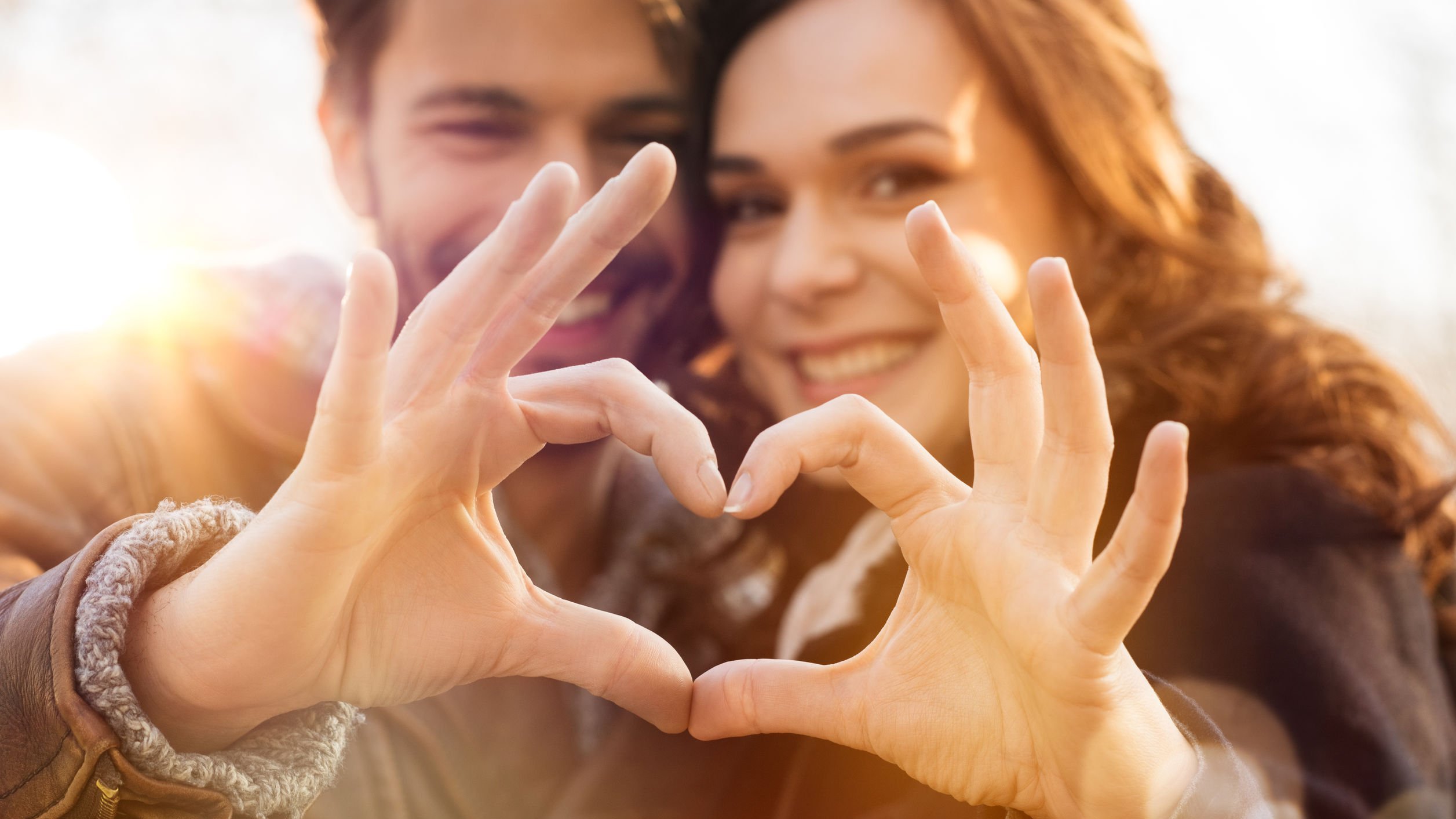 Foto de casal formando um coração com as mãos