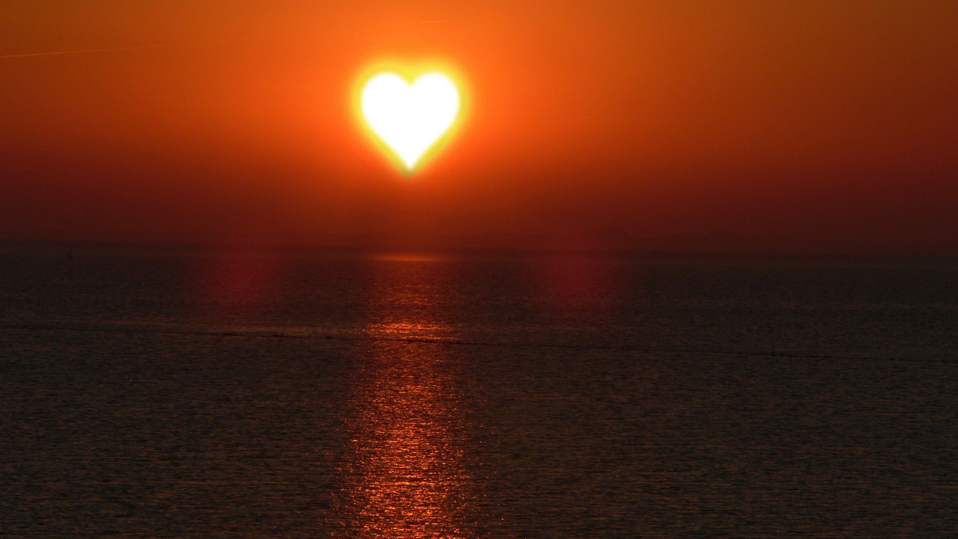 Imagem de um mar e em destaque um coração desenhado sobre o sol.