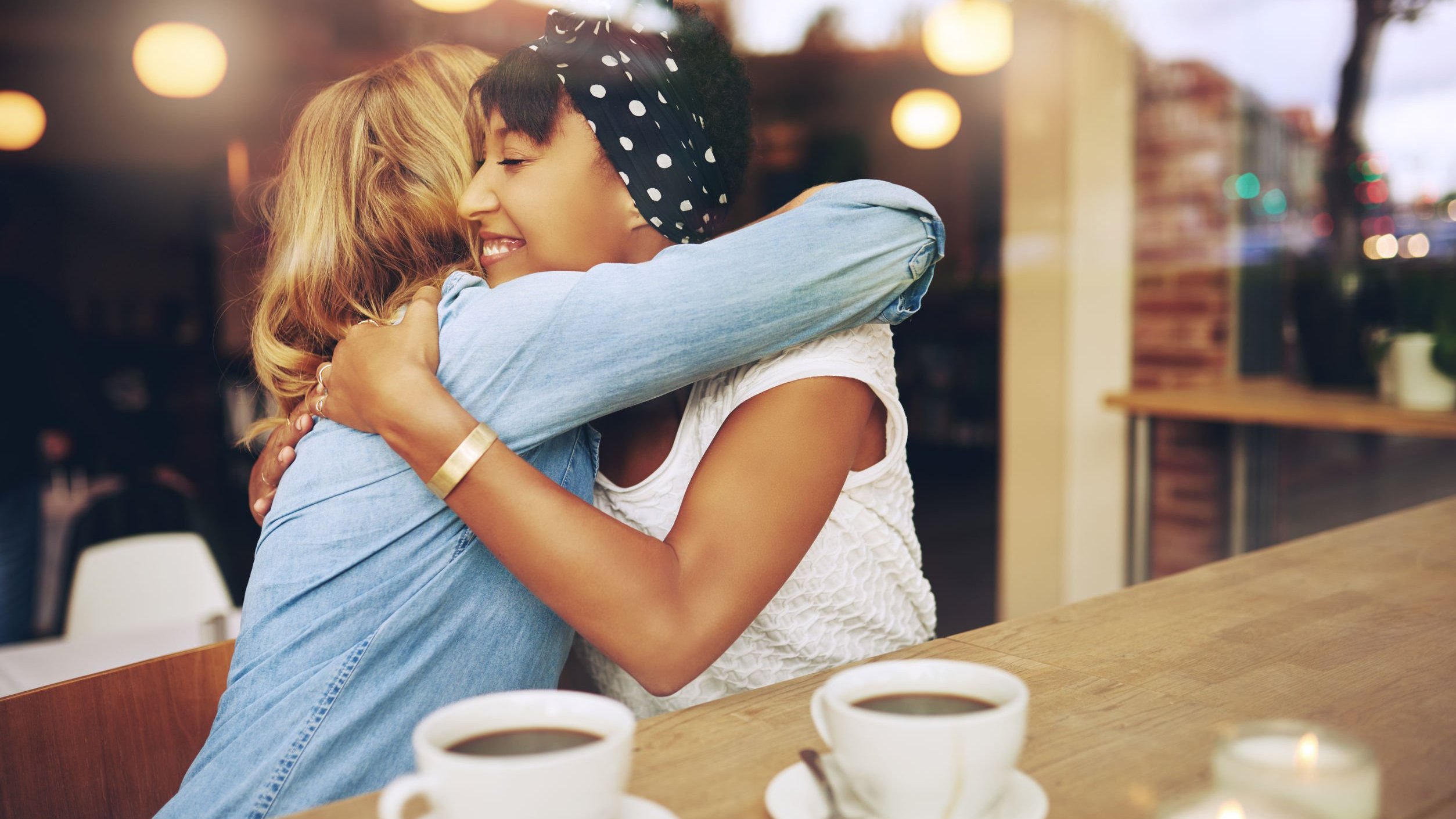 Duas mulheres em um café se abraçando.