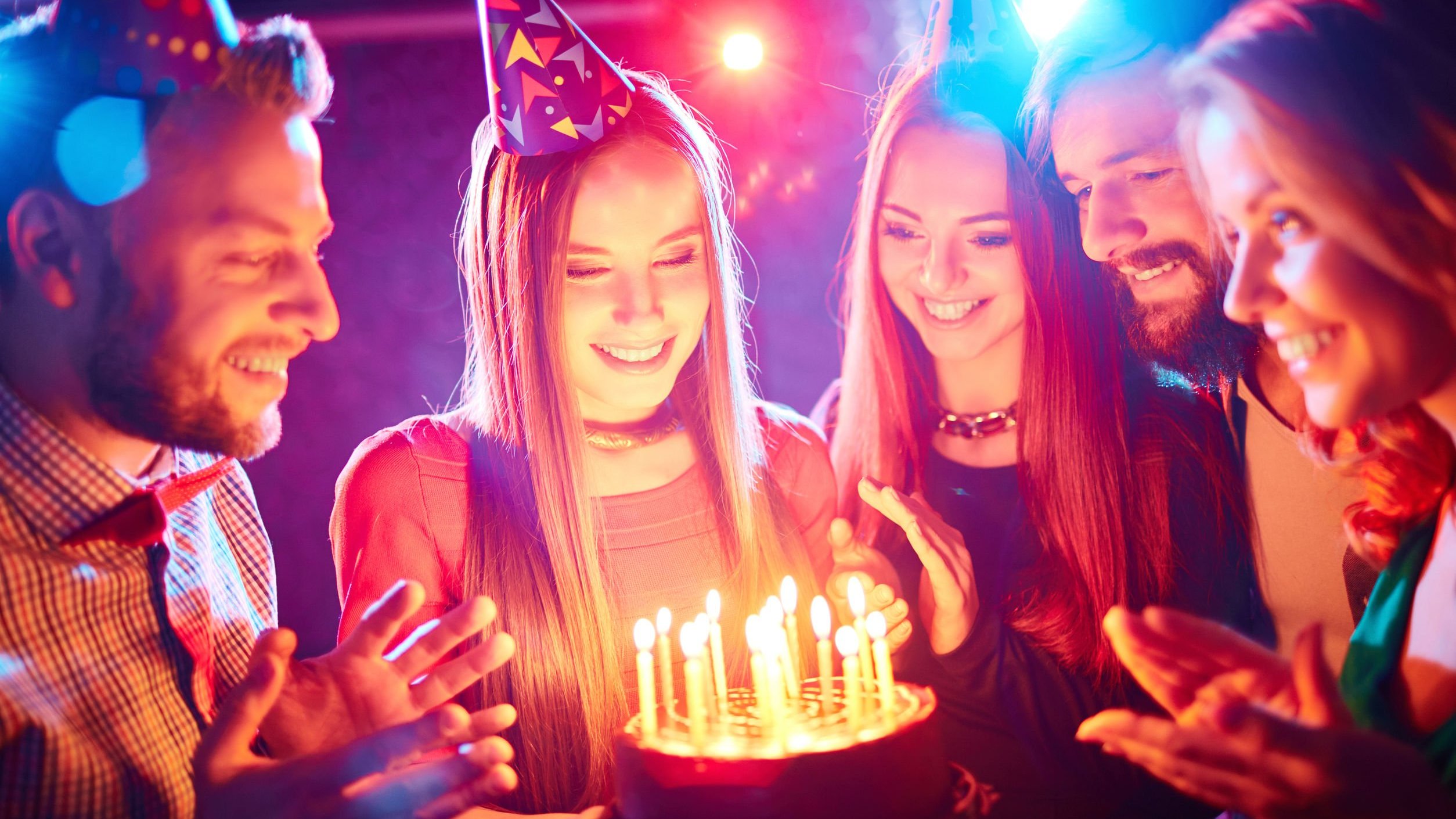 Foto de pessoas cantando parabéns com bolo de aniversário