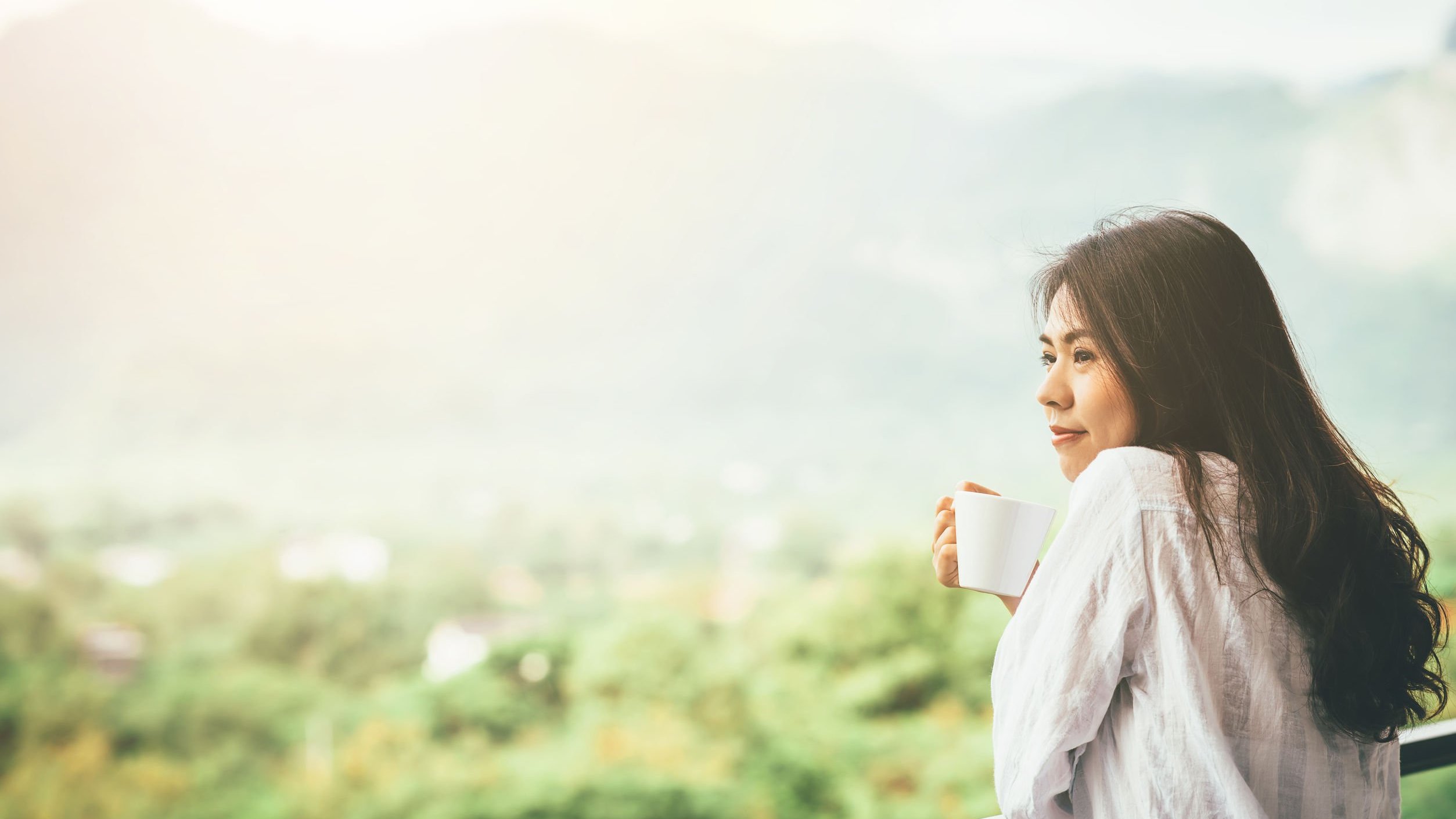 Mulher tomando café na varanda.