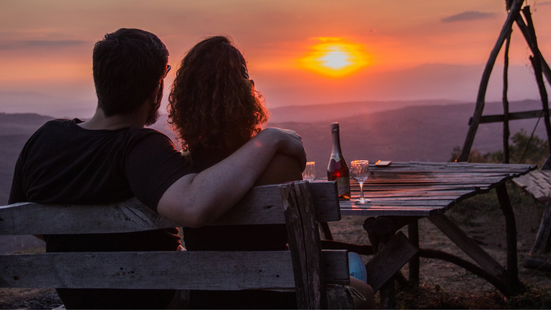 Foto de homem e mulher abraçados assistindo o por do sol