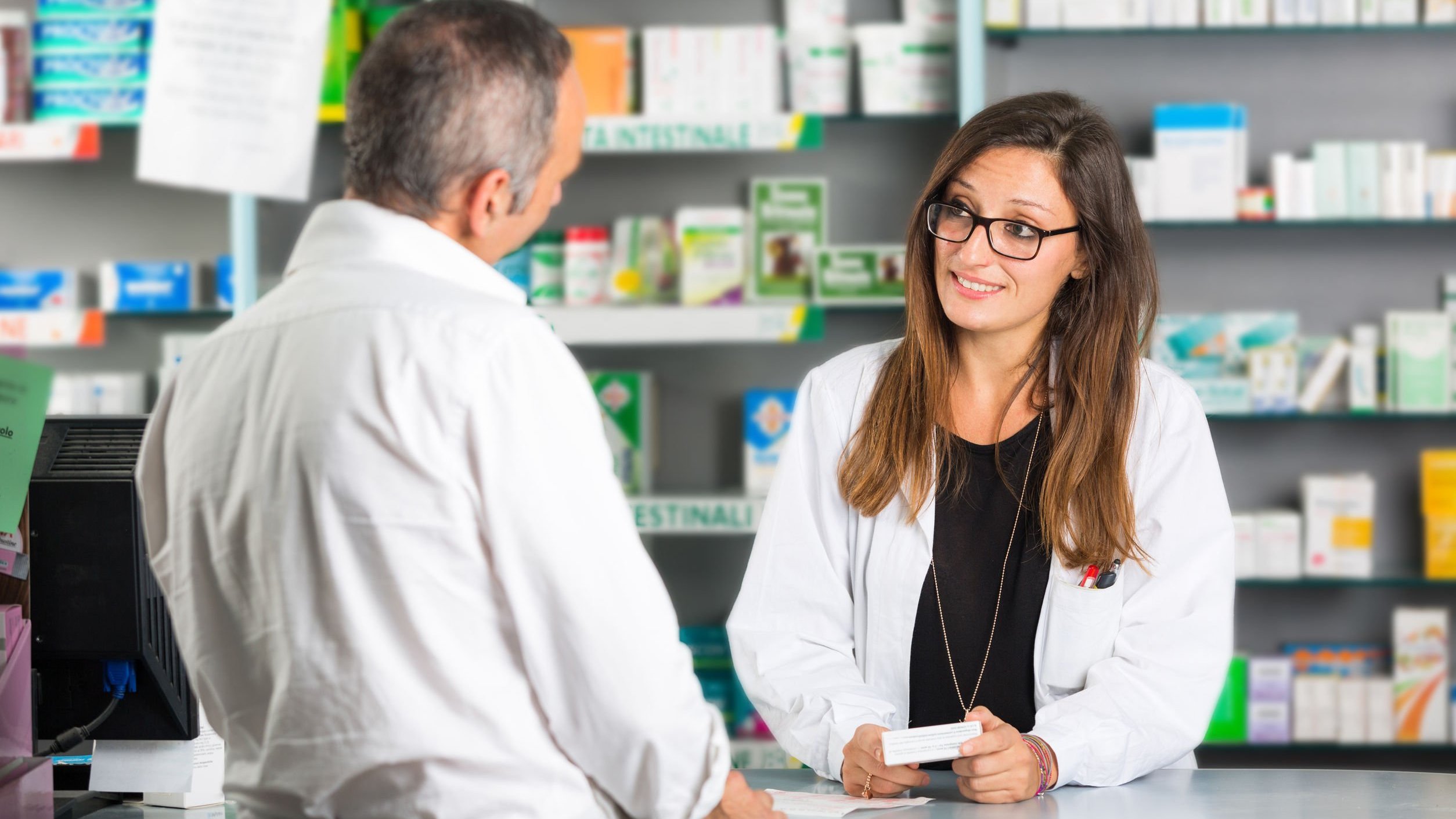 Farmacêutica oferecendo medicamento para cliente.