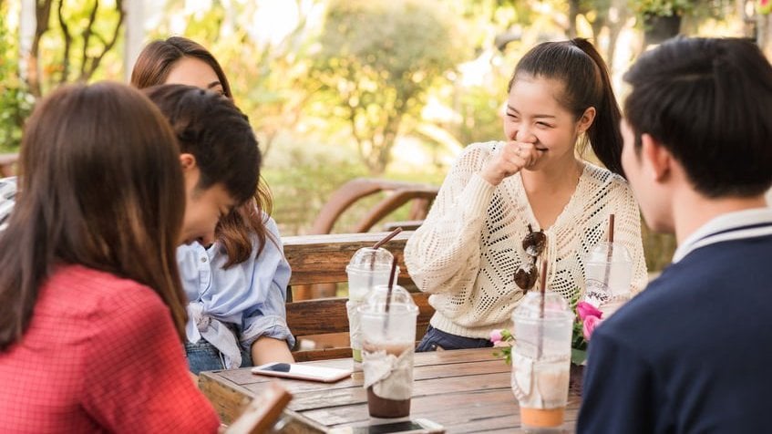 Jovens rindo em mesa de piquenique