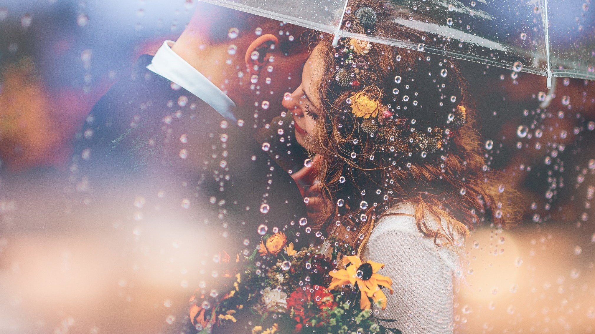 Casal de baixo do guarda-chuva segurando um buquê de flores