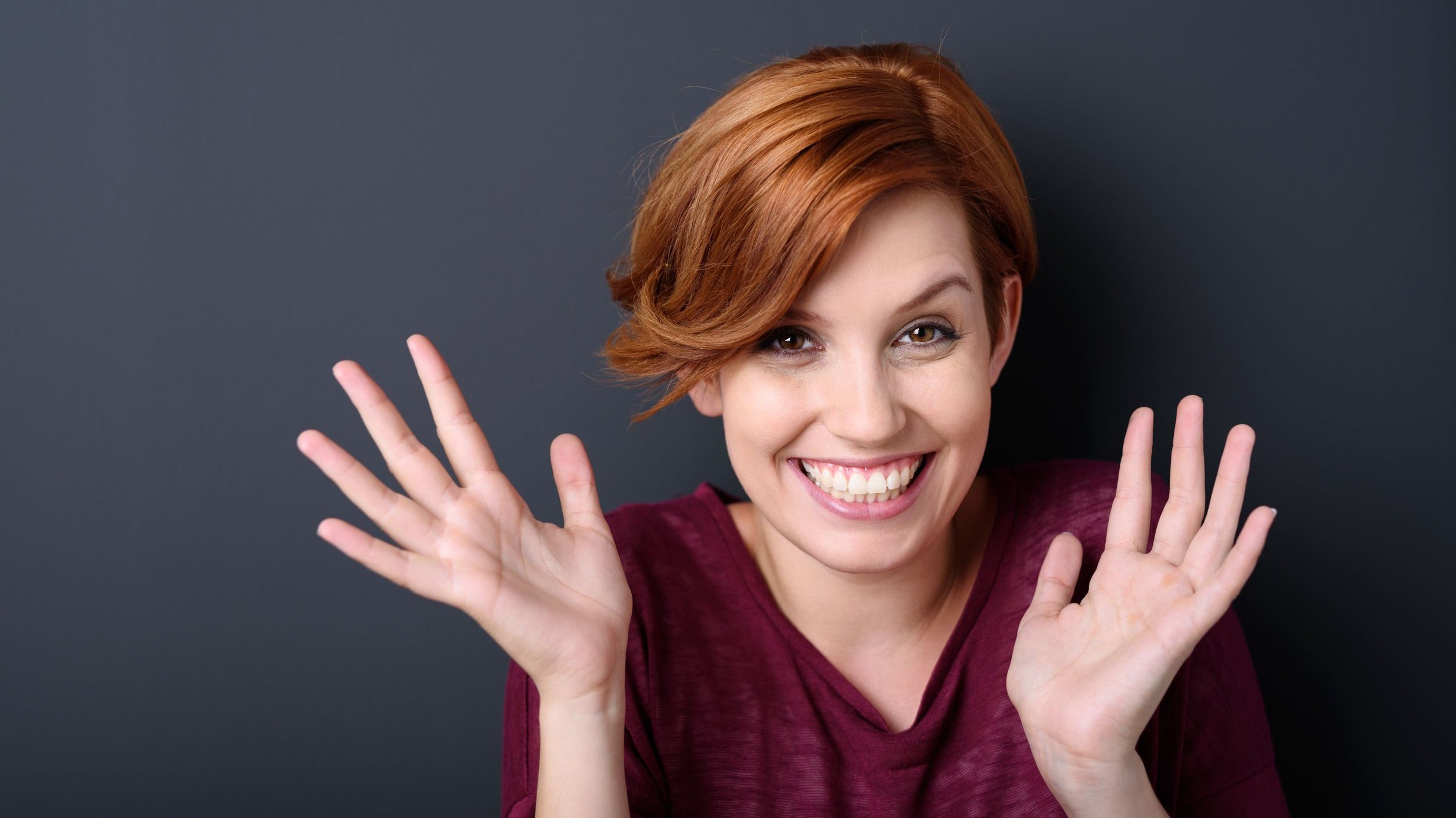 Mulher sorrindo com as mãos abertas em direção ao rosto