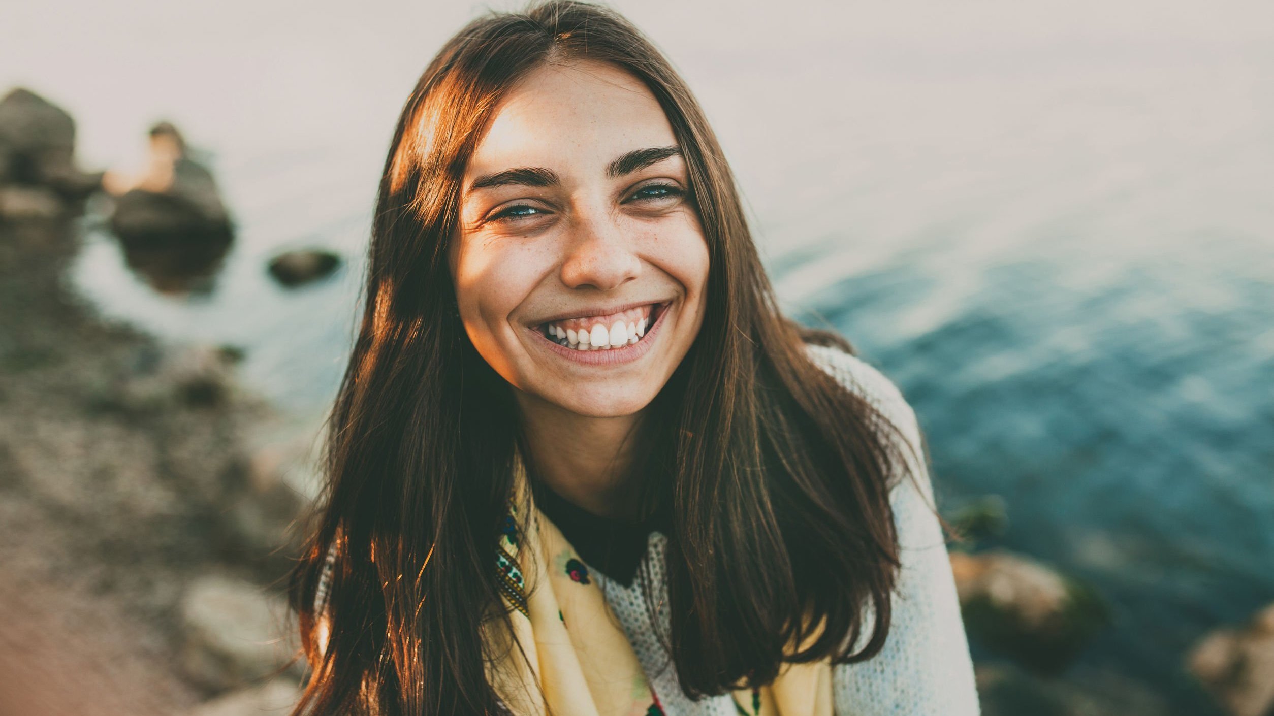 Mulher sorrindo de frente para um lago
