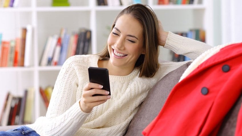 Mulher olhando pra celular e sorrindo