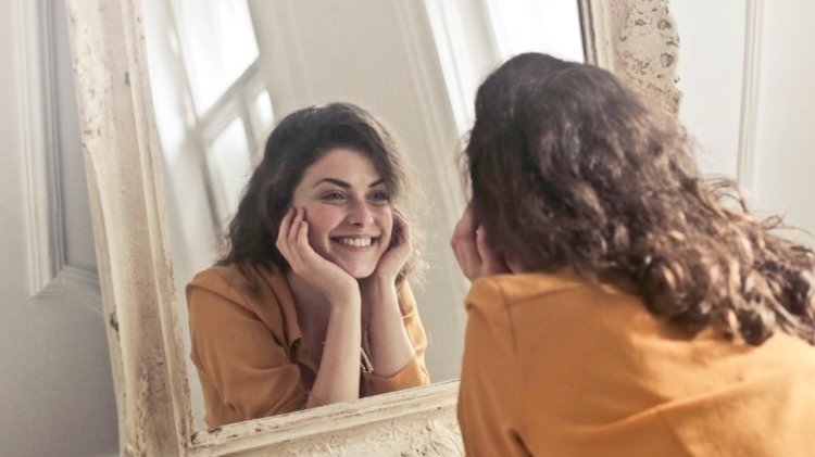Mulher sorrindo para espelho