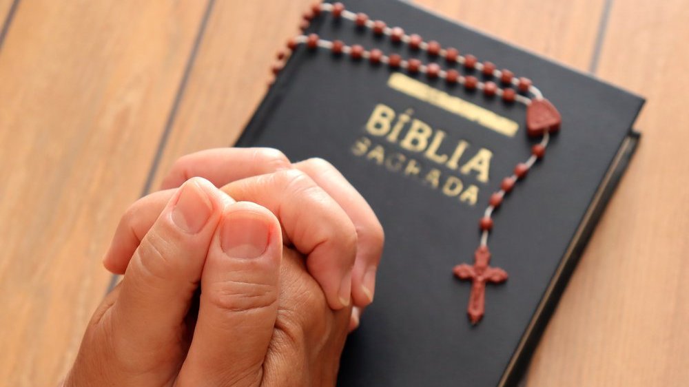 Uma Bíblia e uma pessoa rezando