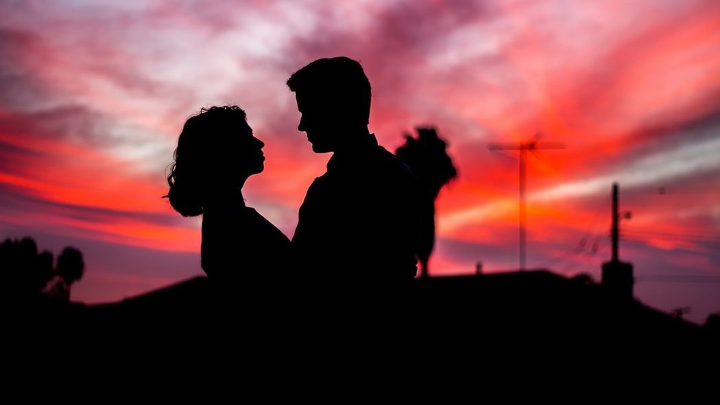 Silhuta de casal se olhando durante um pôr do sol.