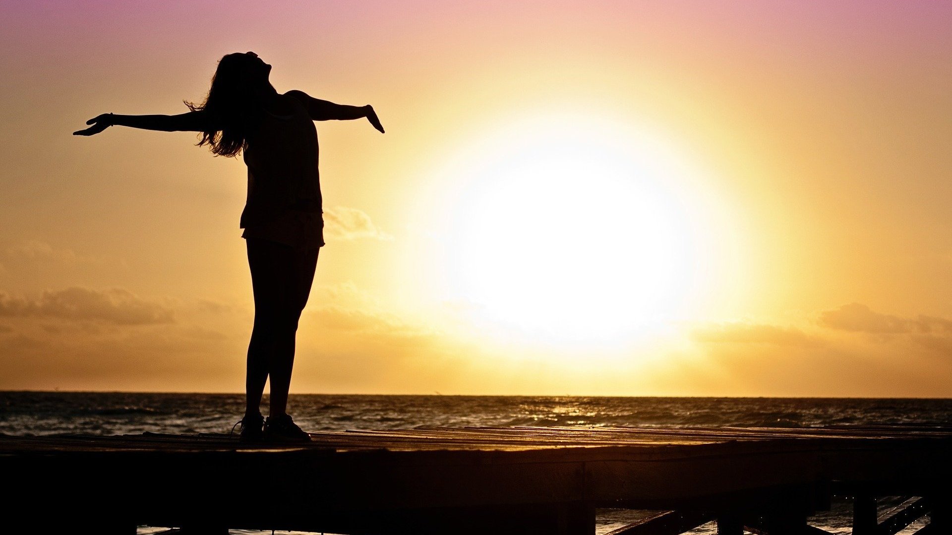 Imagem do sol e mulher de braços abertos