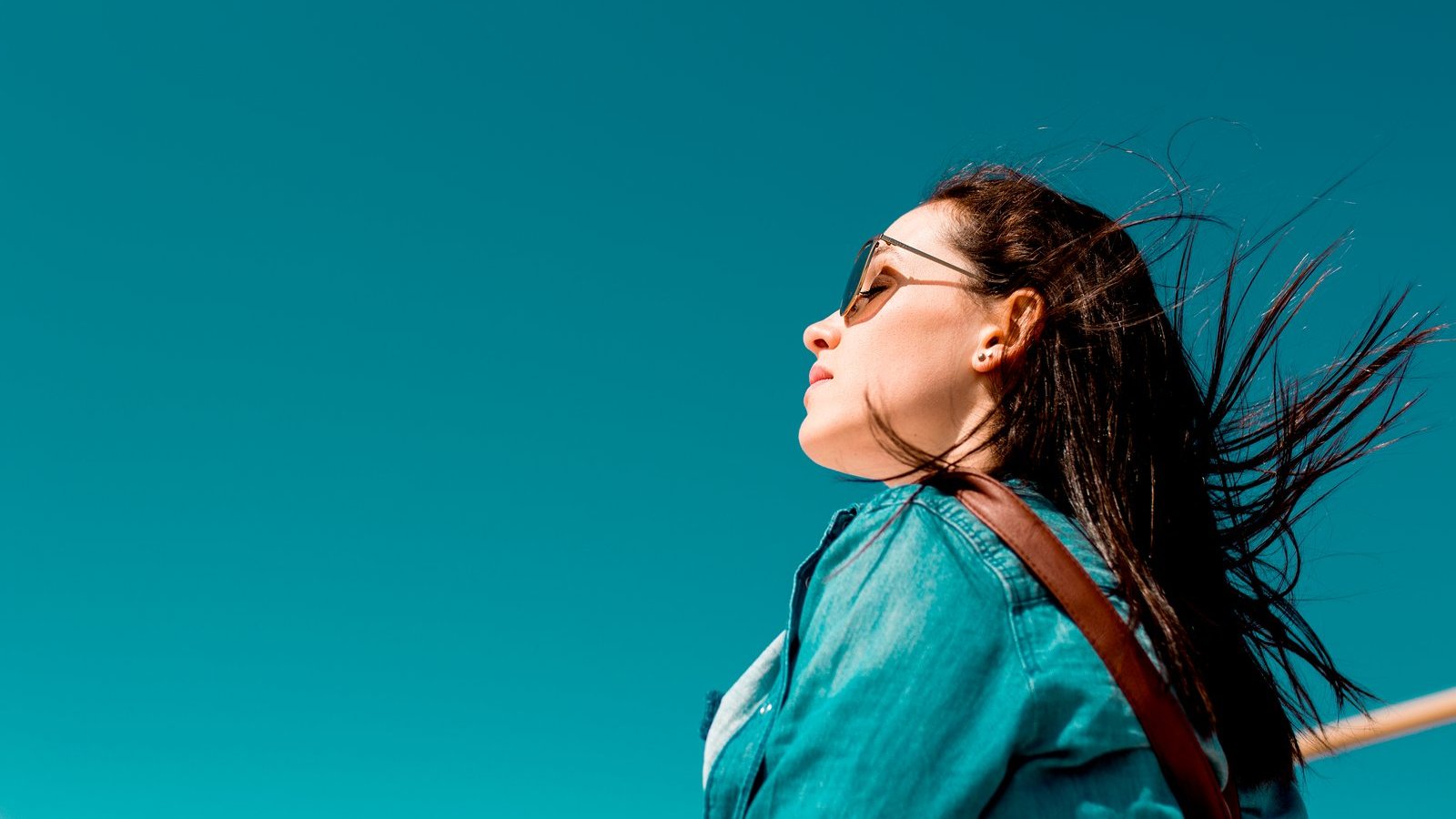 João Jesus / Canva PRO Mulher branca de cabelos longos e pretos usando óculos de sol.