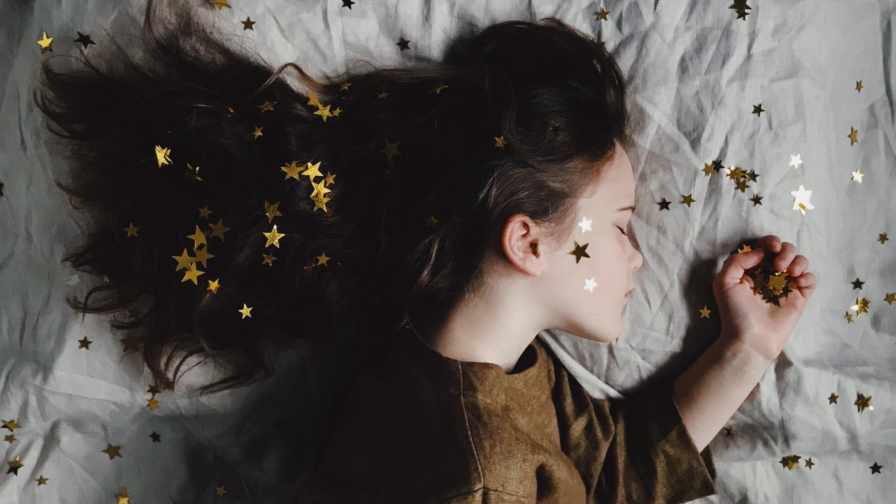 Mulher deitada na cama com estrelas no cabelo, no rosto e na cama