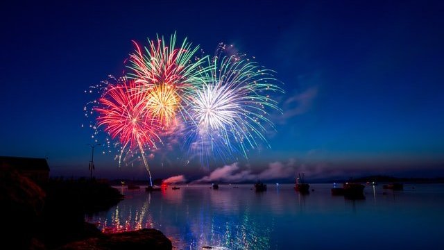 Um vasto mar com fogos de artifícios queimando ao fundo