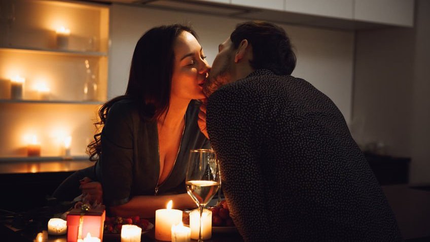 Casal se beijando em jantar a luz de velas