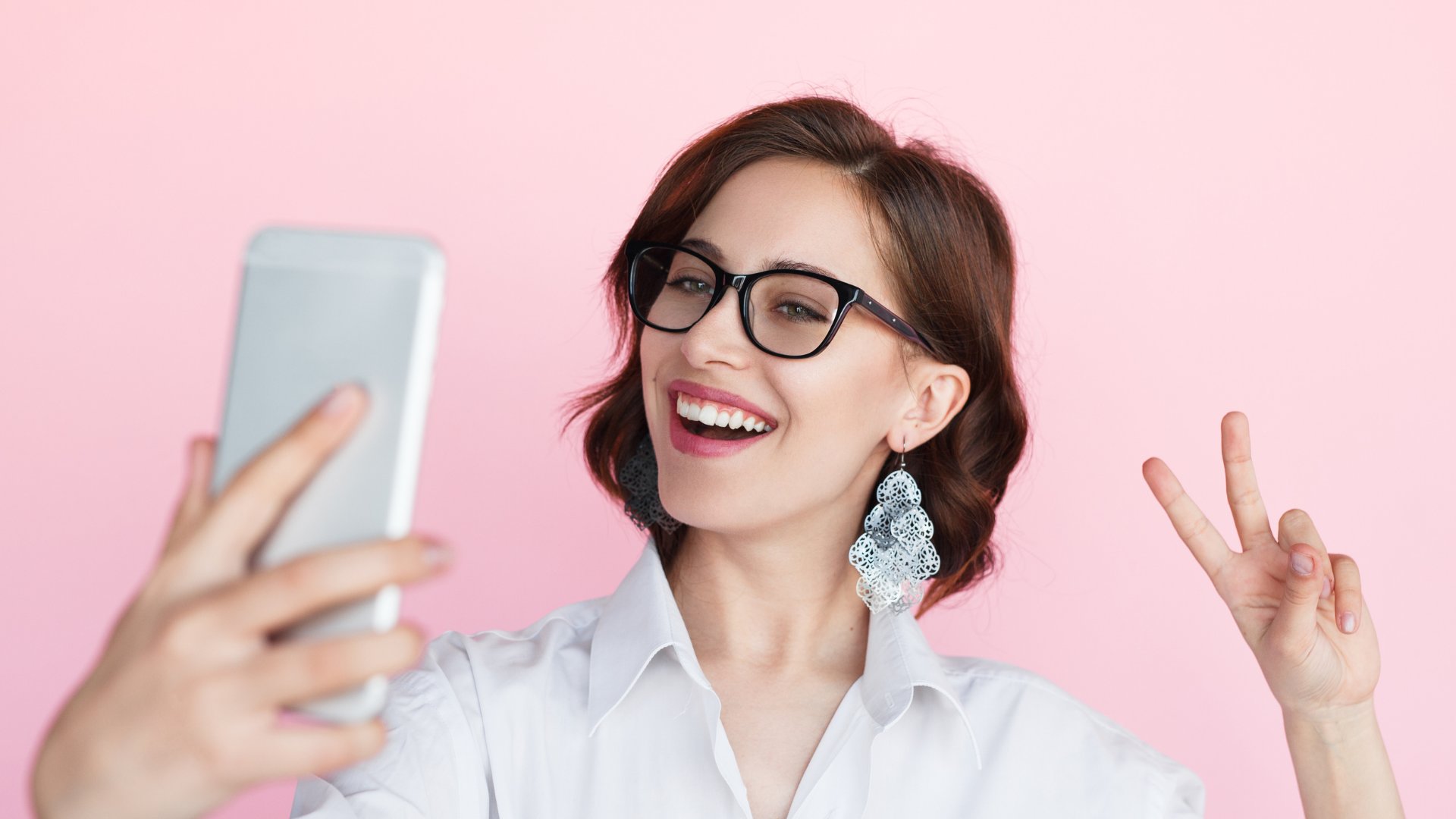 Max-kegfire / Getty Images Pro / Canva Mulher tirando selfie e sorrindo