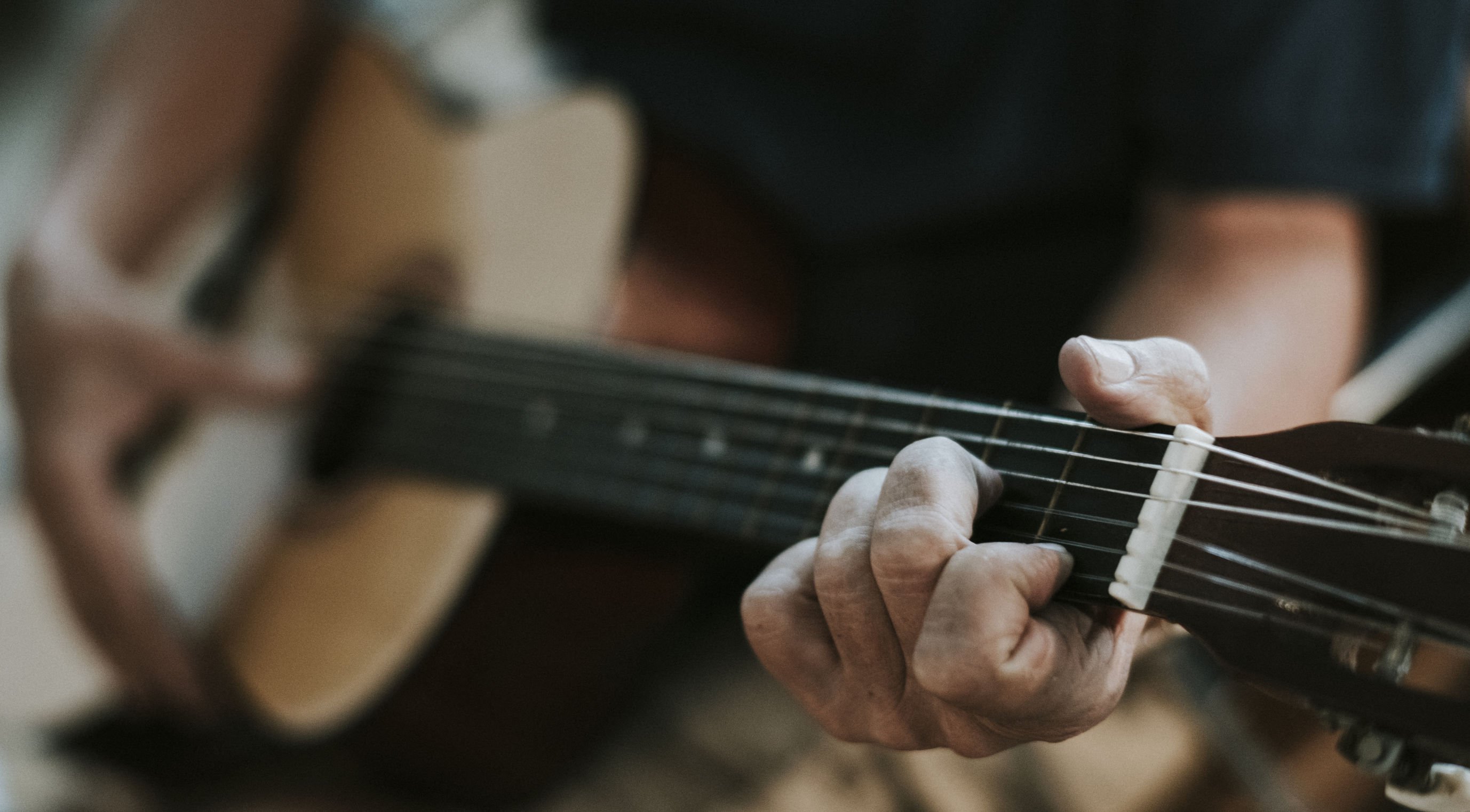 Homem branco tocando violão.