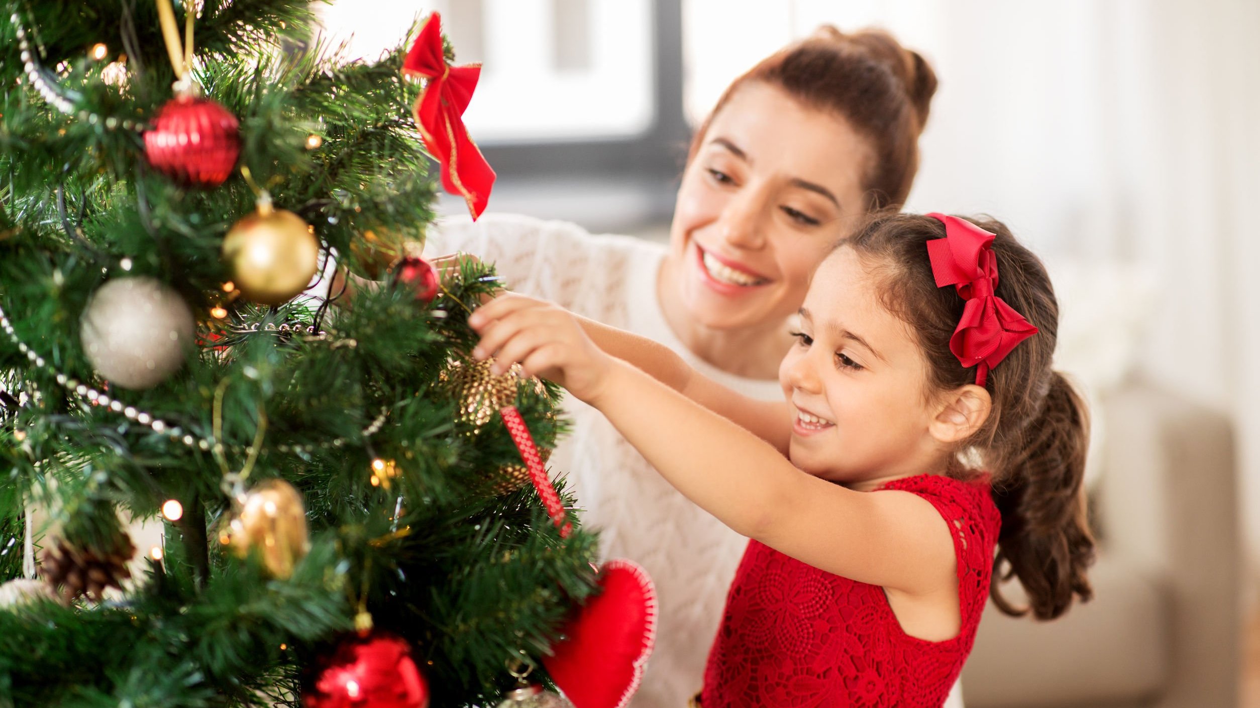 Mãe e filha felizes decorando arvore de natal