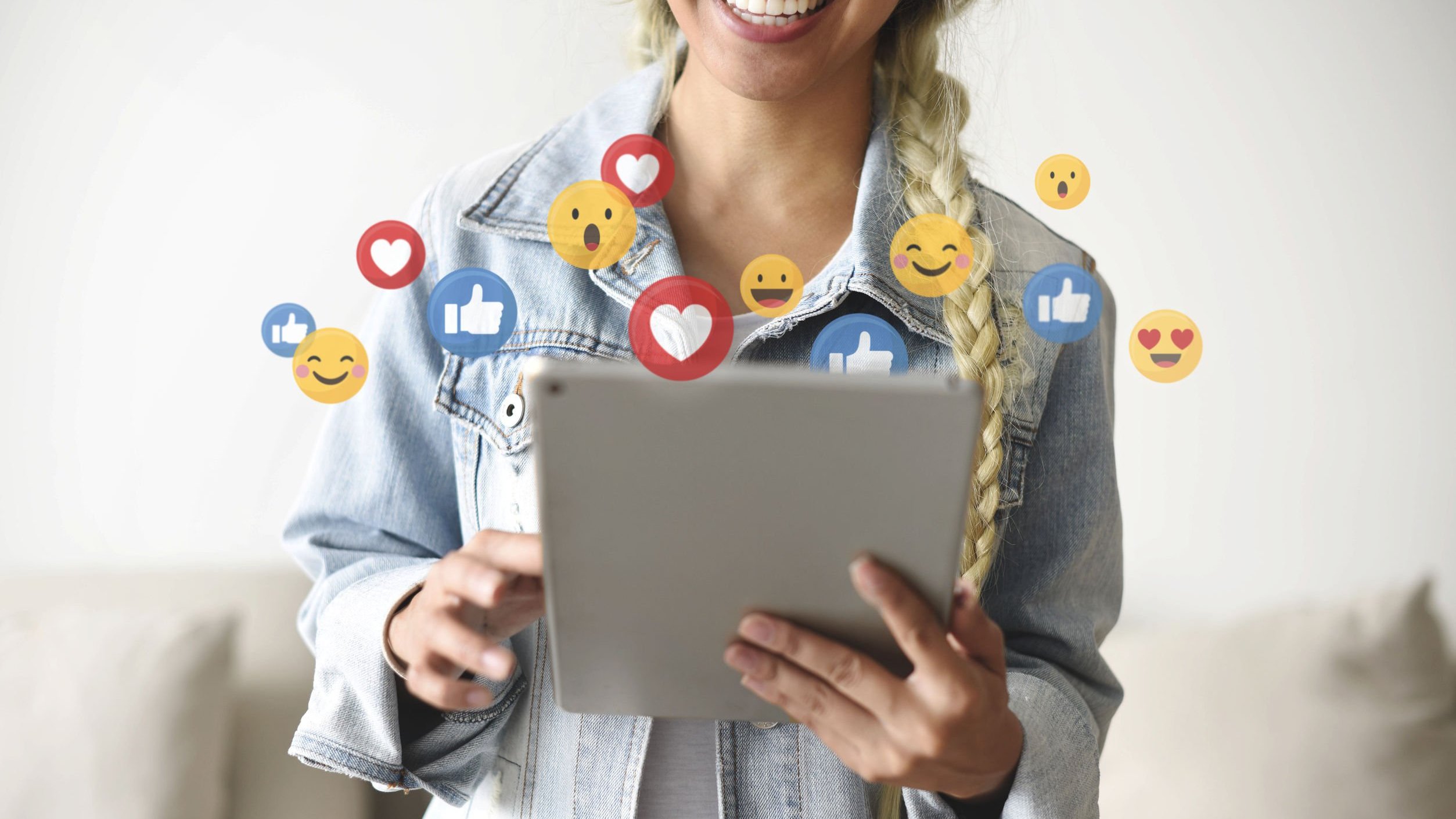 Mulher segurando tablet com vários emojis em sua volta