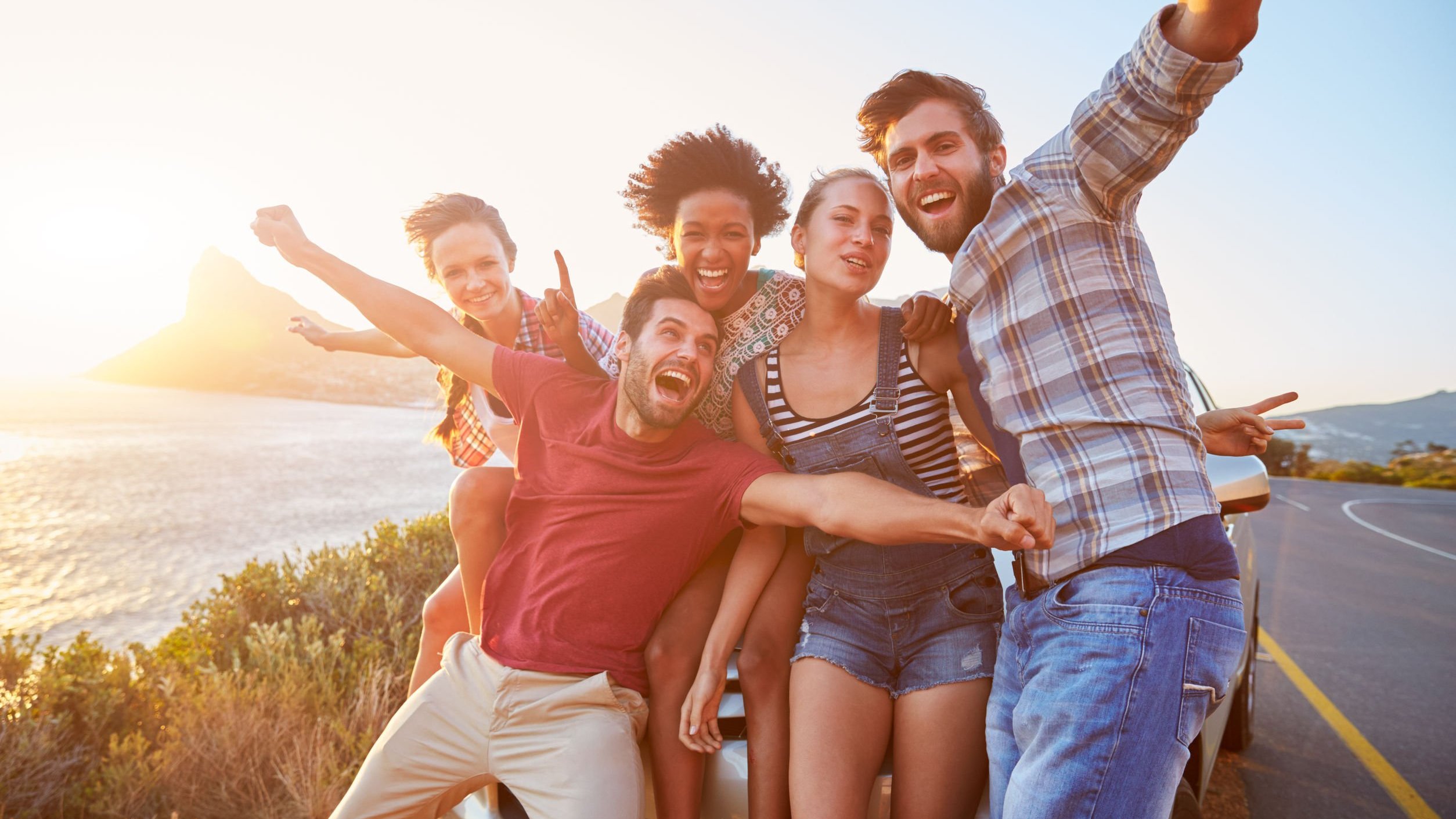Grupo de pessoas com os abraços abertos e sorrindo na estrada