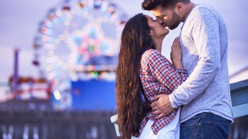 Casal se beijando em um parque de diversões