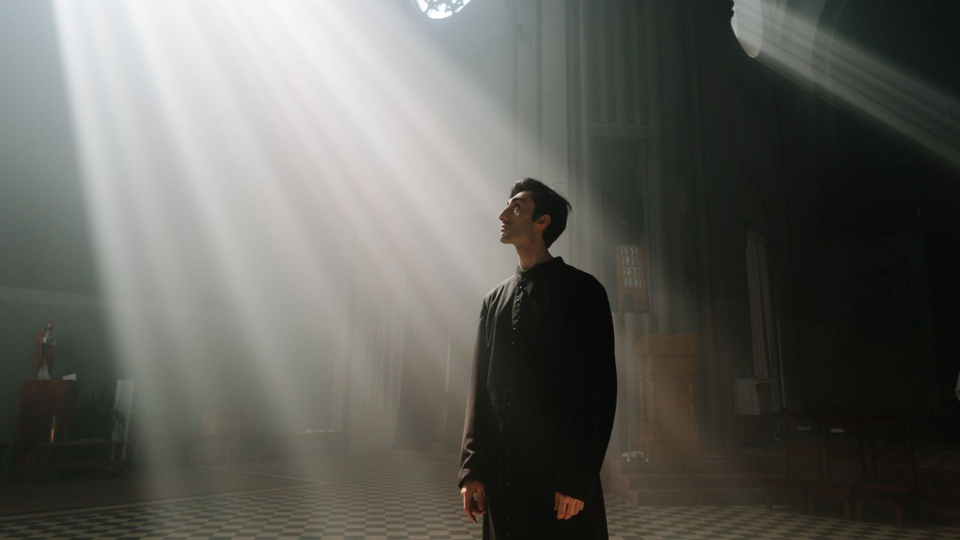 Imagem de um homem dentro de uma igreja olhando para cima e um feixe de luz sobre ele.
