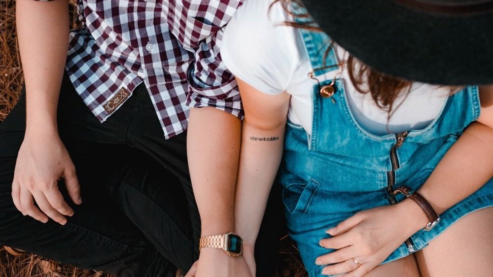 Camila Cordeiro/Unsplash. Casal sentados de mãos dadas.