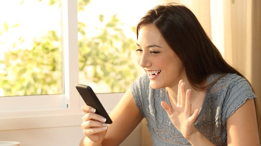 Moça sorrindo enquanto usa seu smartphone.