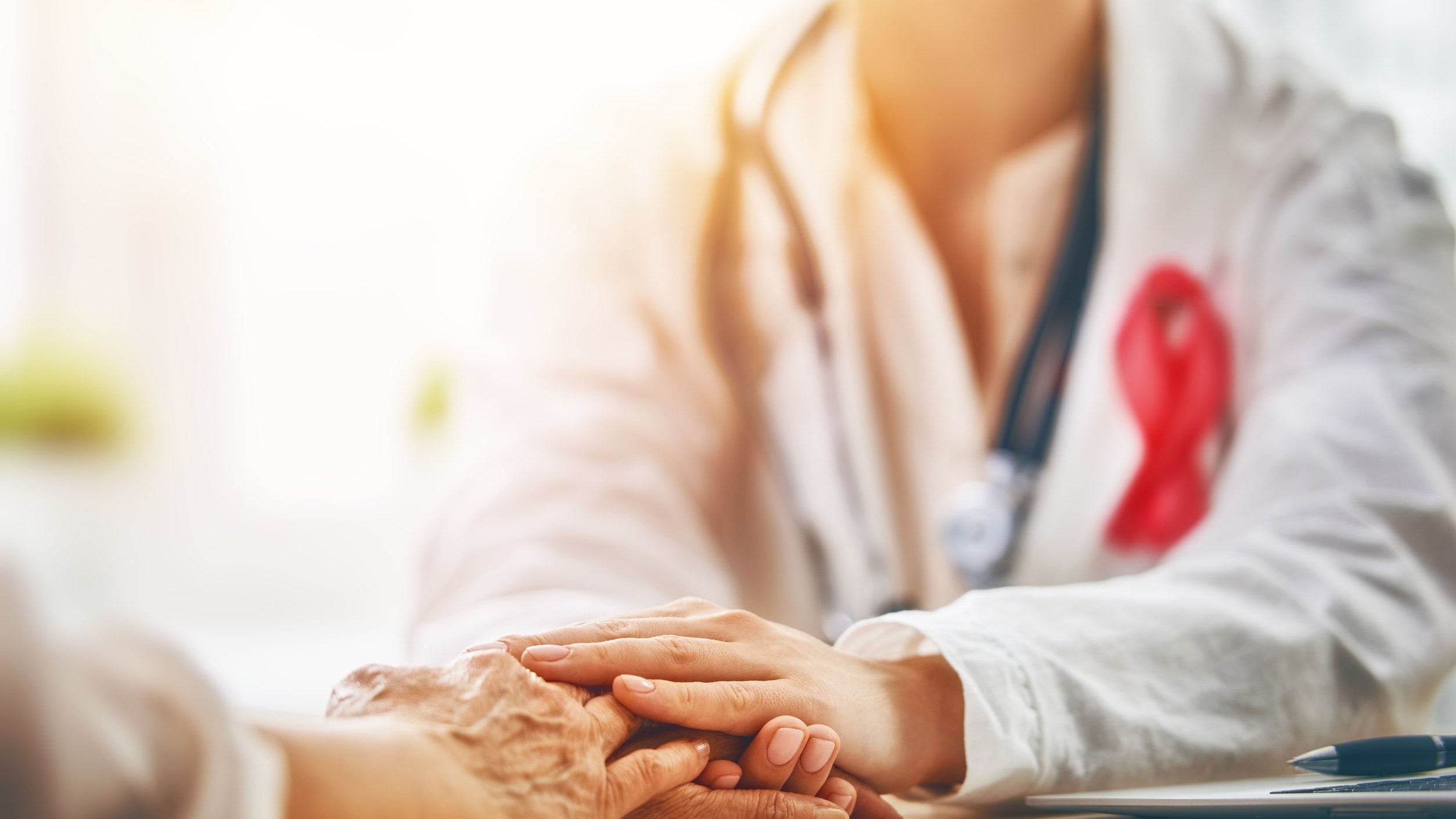 Médica segurando mãos de paciente.