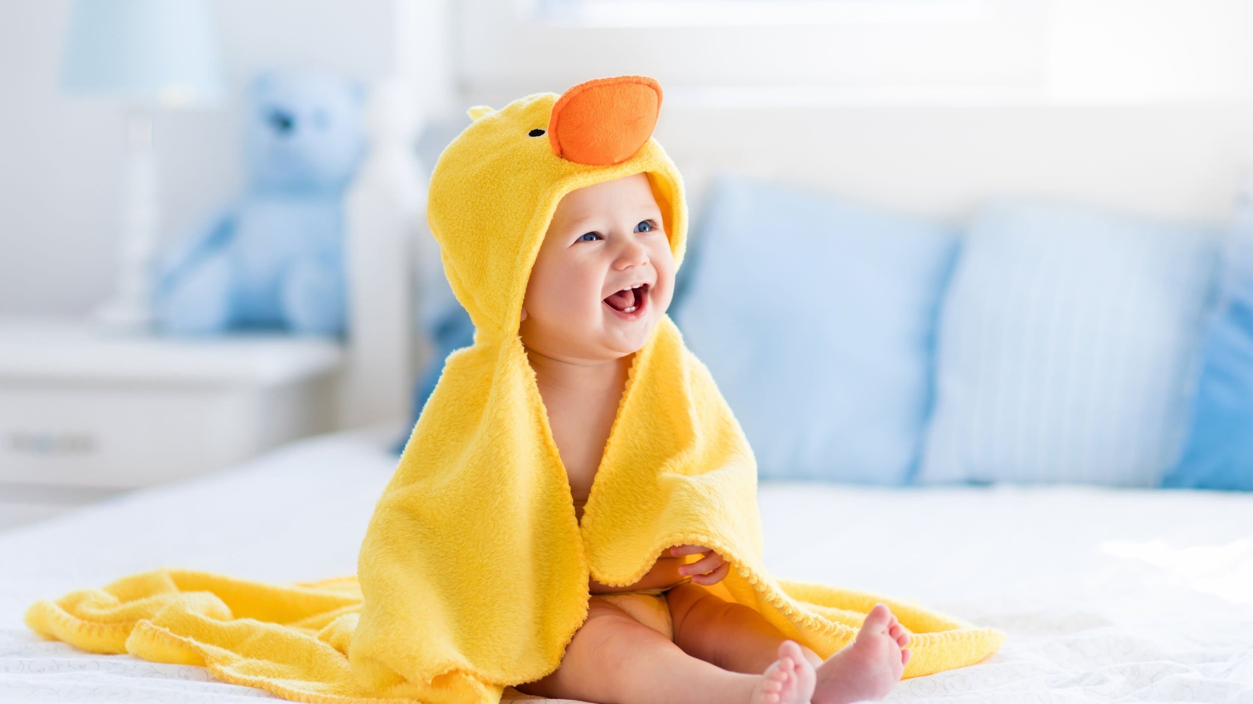 Bebê sorrindo envolvido em uma roupinha de pato