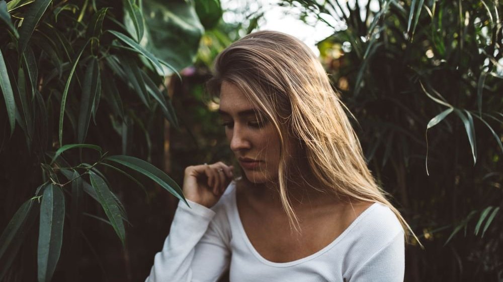 Mulher olhando para baixo no meio de plantas