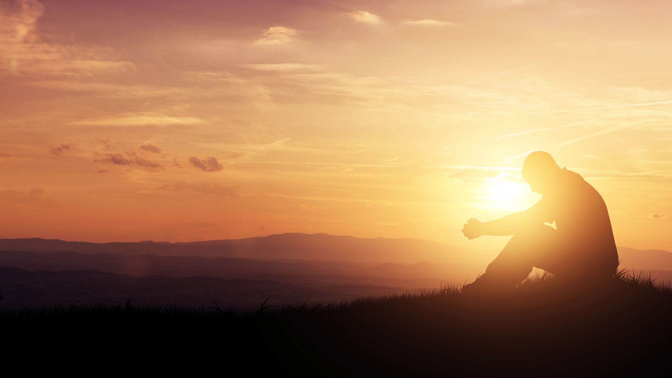 Homem rezando sob o nascer do sol.