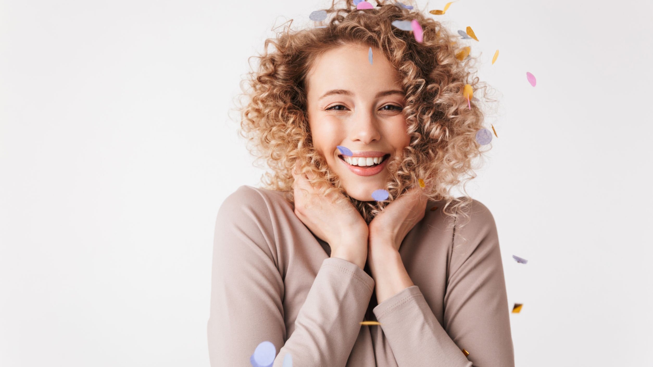 Mulher sorrindo com confete colorido caindo em sua cabeça