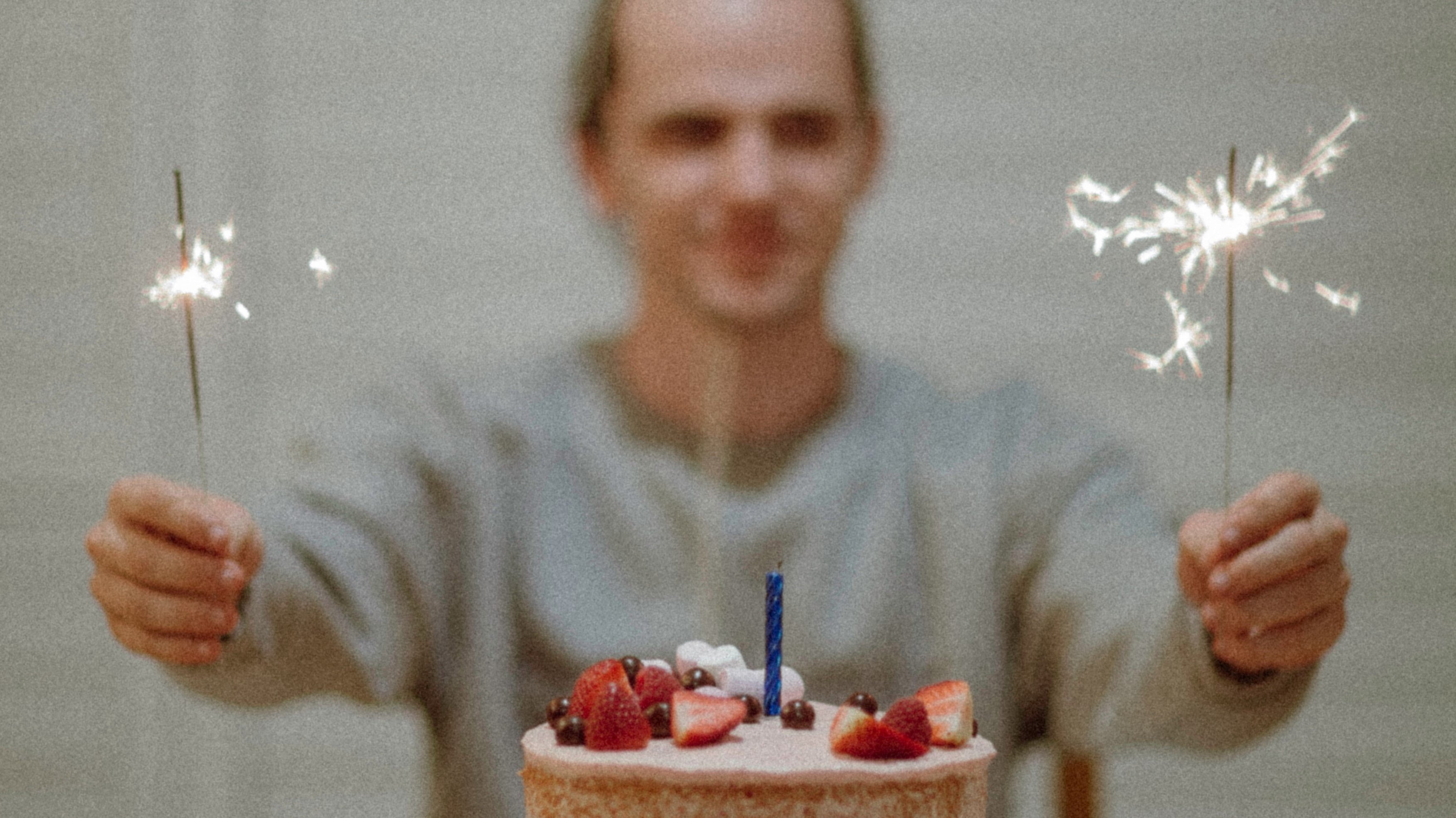 Homem segurando velas e mesa de bolo em sua frente