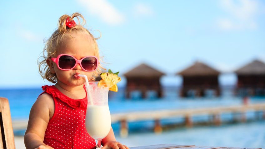 Criança na praia bebendo um suco