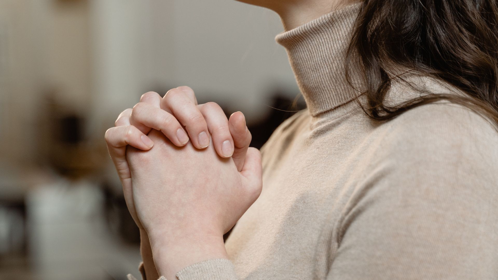Imagem de uma mulher com as mãos juntas em sinal de oração