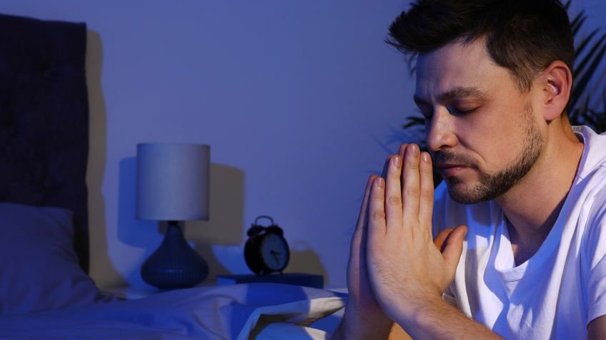 Homem orando na cama