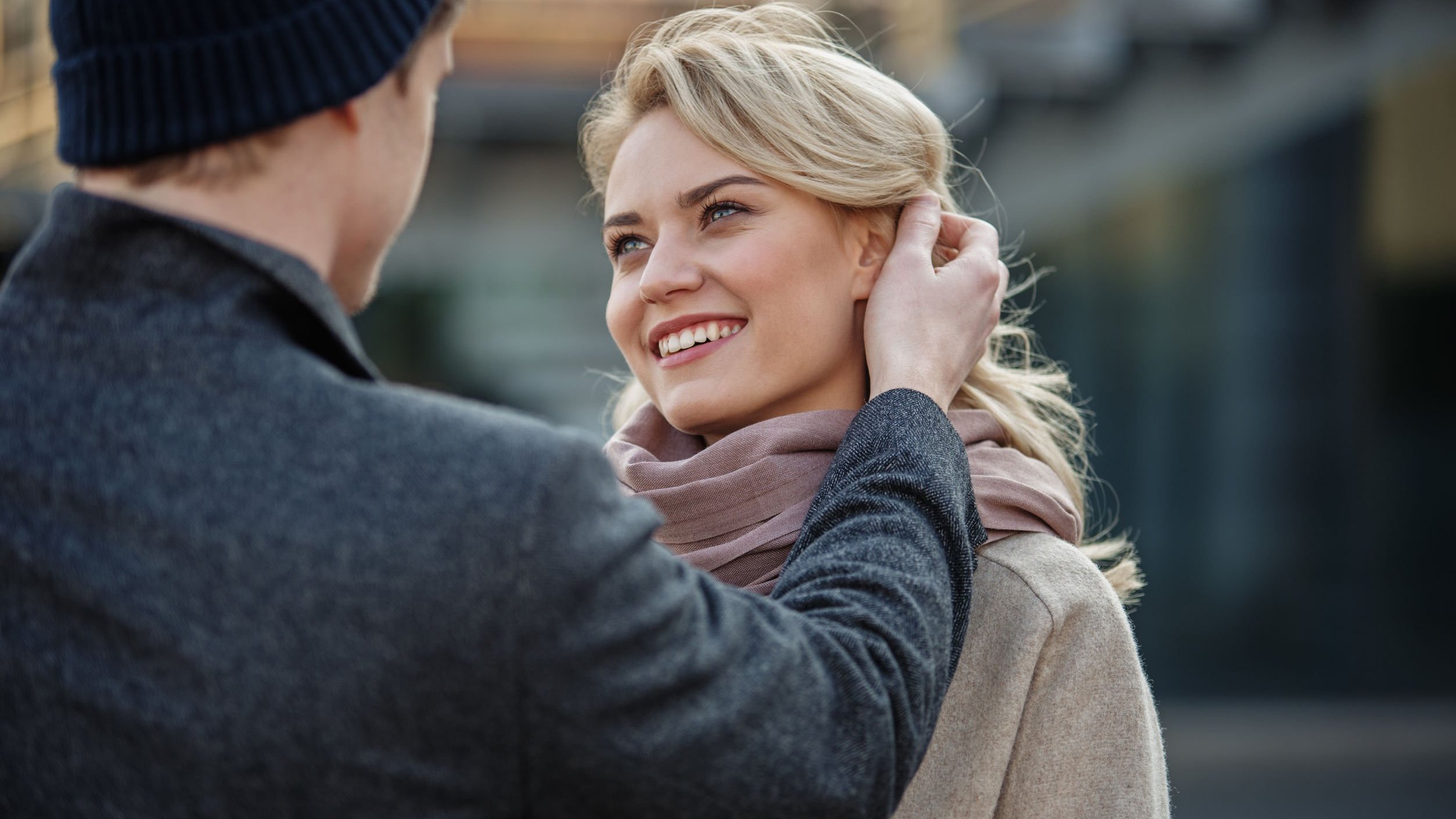 Homem mexendo no cabelo de uma mulher, que sorri.