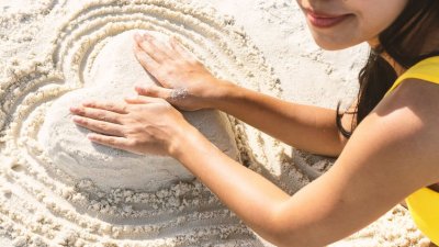 123rf Mulher fazendo coração de areia