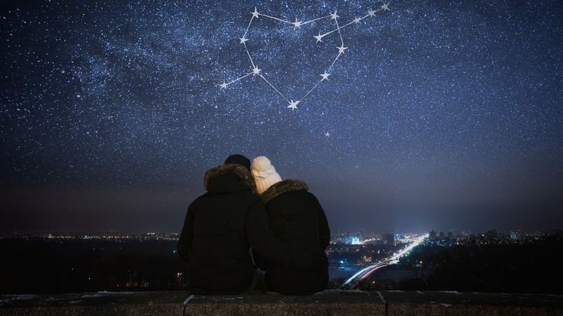 Casal sentados olhando um céu estrelado